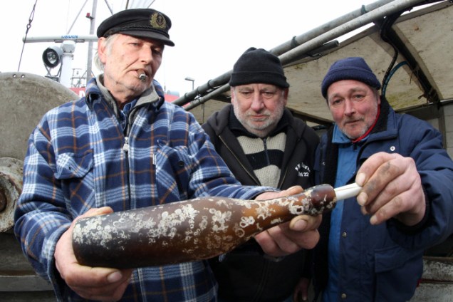 Konrad Fischer, Klaus Matthiesen e Thomas Buick seguram a mensagem da antiga garrafa no barco de pesca Maria I, em Kiel, Alemanha.