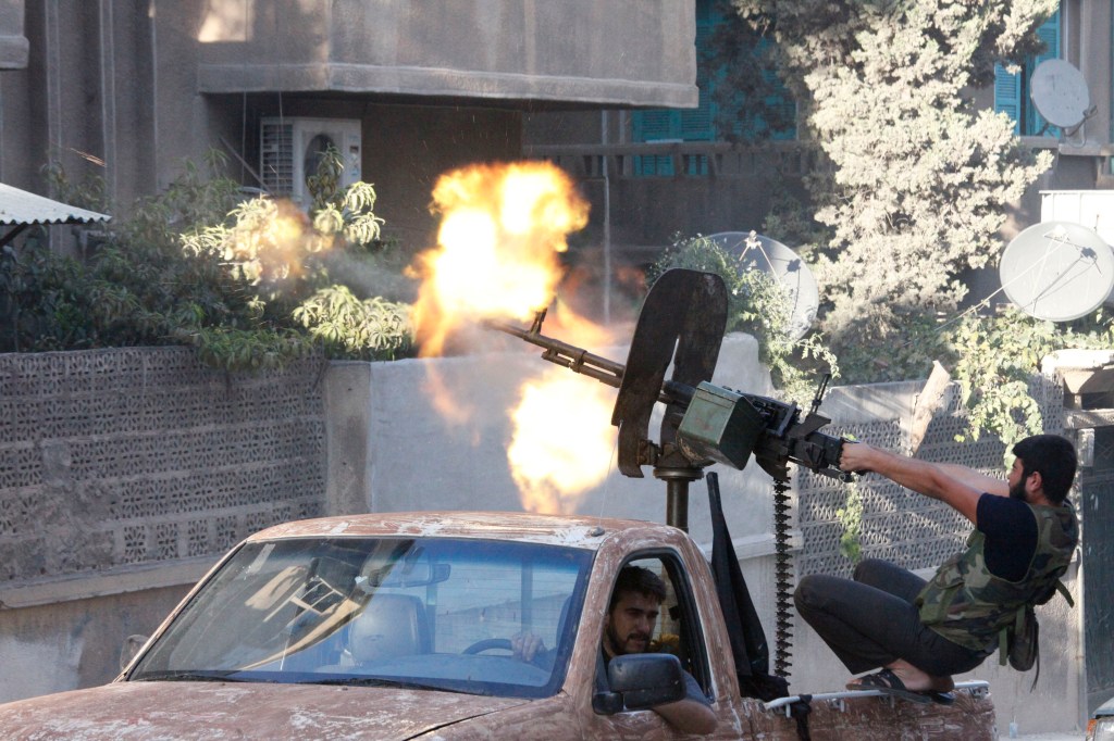 A MEMBER OF FREE SYRIAN ARMY OPEN FIRE FROM HIS MACHINE GUN DURING CLASHES WITH SYRIAN ARMY FORCES IN ALEPPO